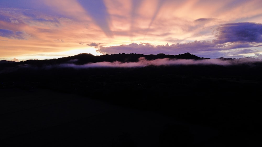 silhouette of mountains under cloudy sky during daytime