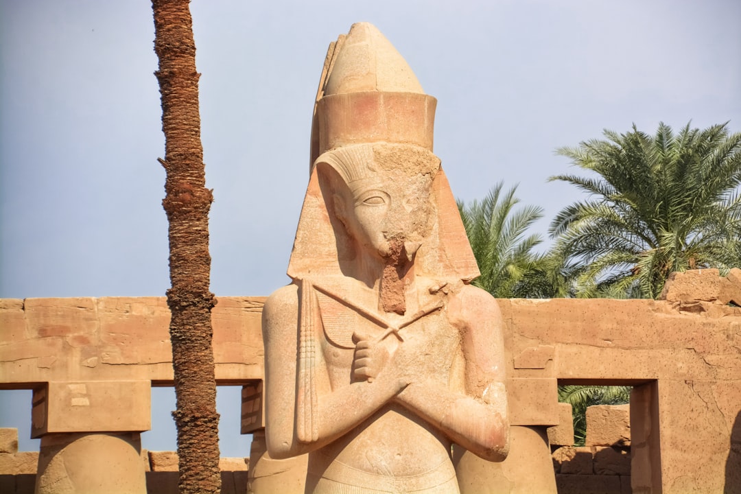 brown concrete statue near green palm tree during daytime