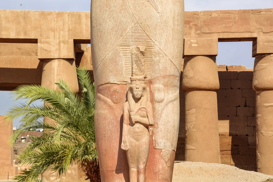 brown concrete statue near green plants during daytime