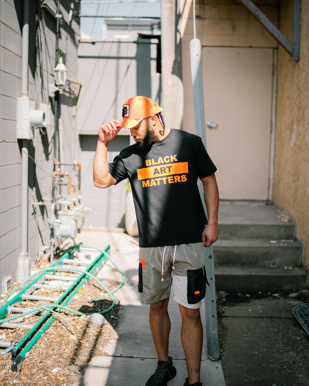 man in black crew neck t-shirt and orange helmet standing on stairs during daytime