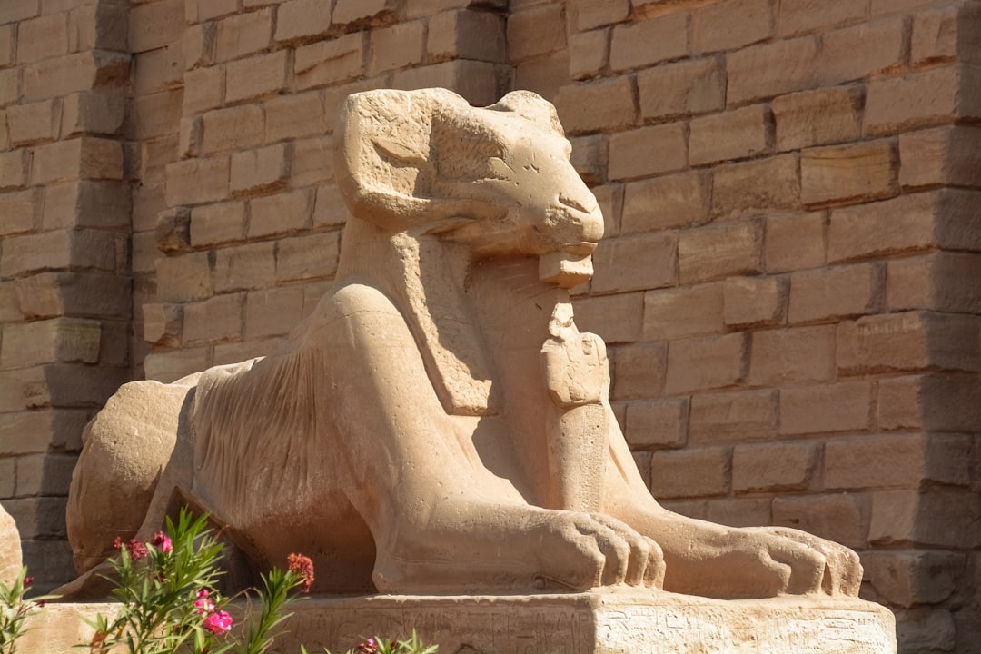 brown concrete statue near green plants during daytime