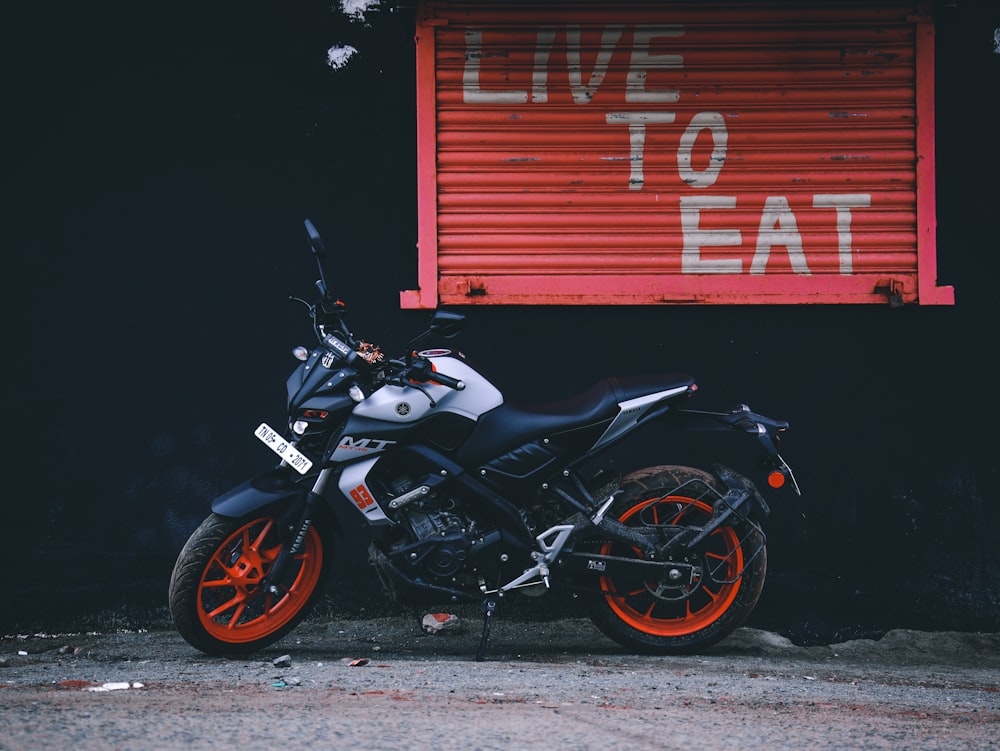 black and white motorcycle parked beside red roll up door