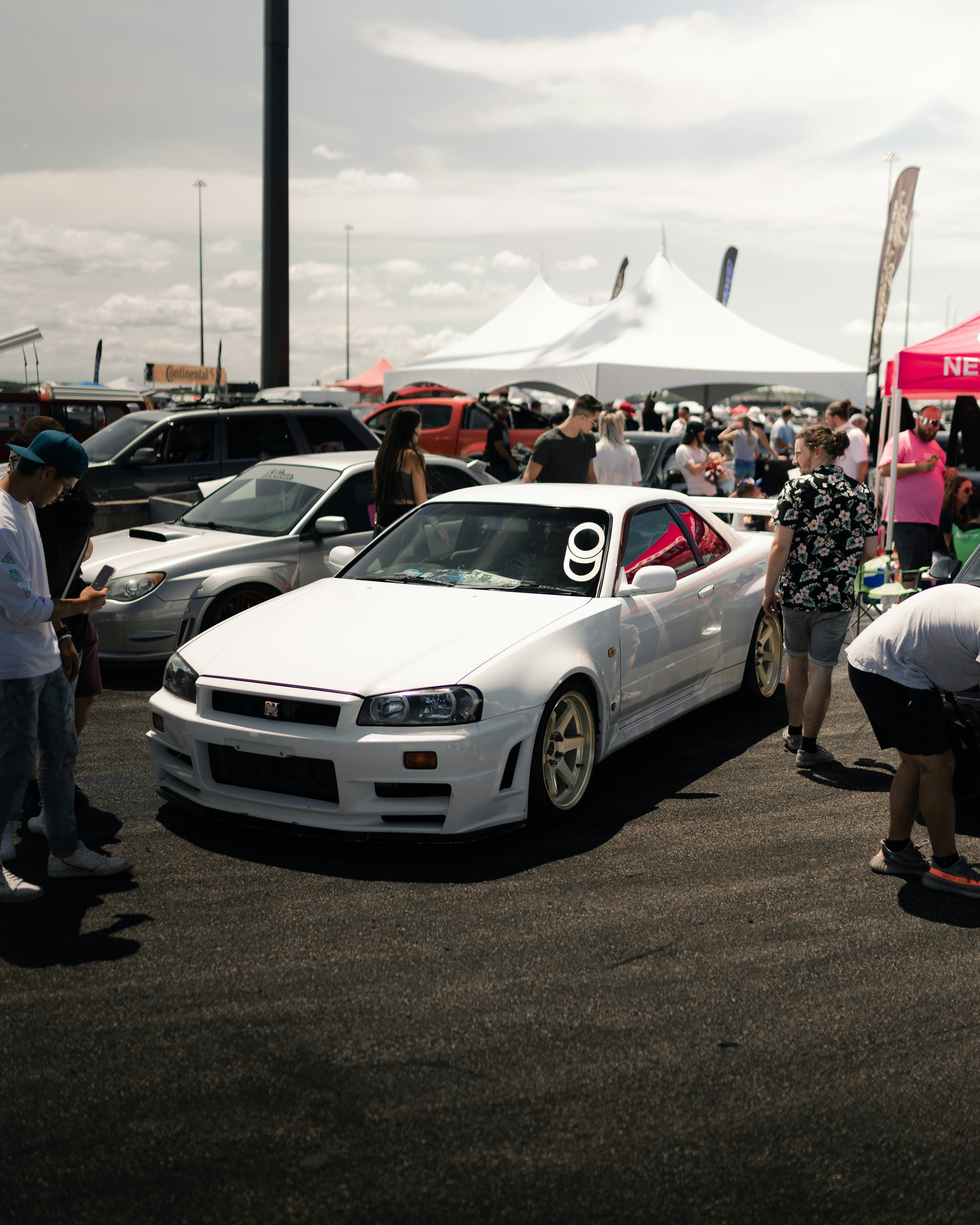 people standing beside white bmw coupe during daytime