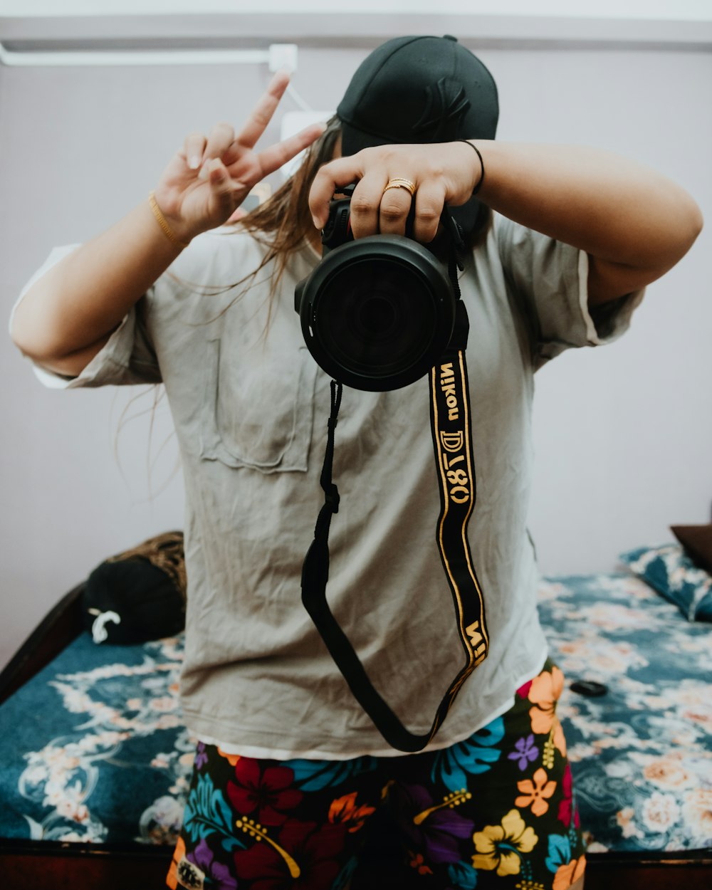 Hombre con camiseta blanca de cuello redondo sosteniendo una cámara DSLR negra