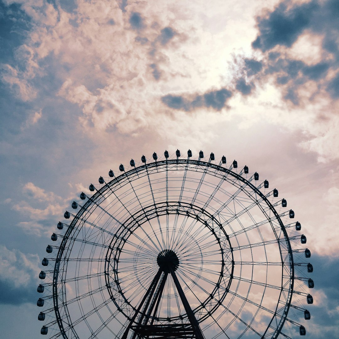 white and black ferris wheel under white clouds and blue sky during daytime