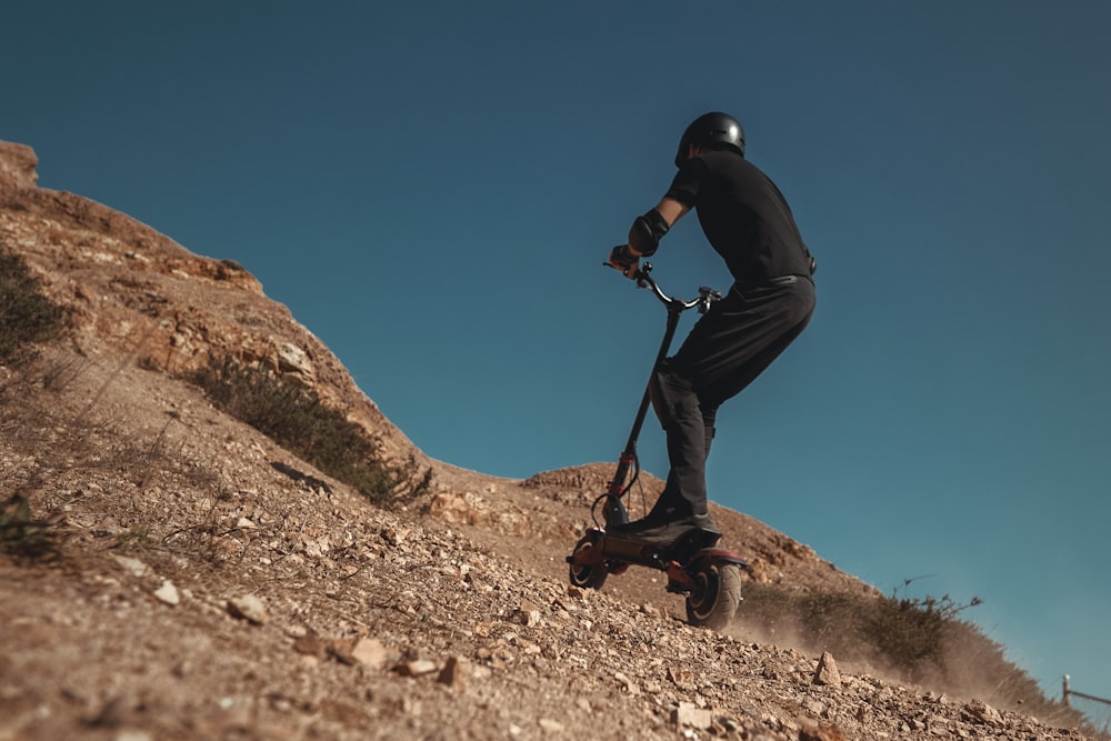 man in blue jacket and black pants climbing on brown rock mountain during daytime