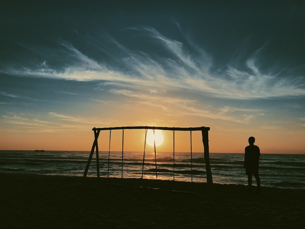 silhouette of 2 people standing on beach during sunset