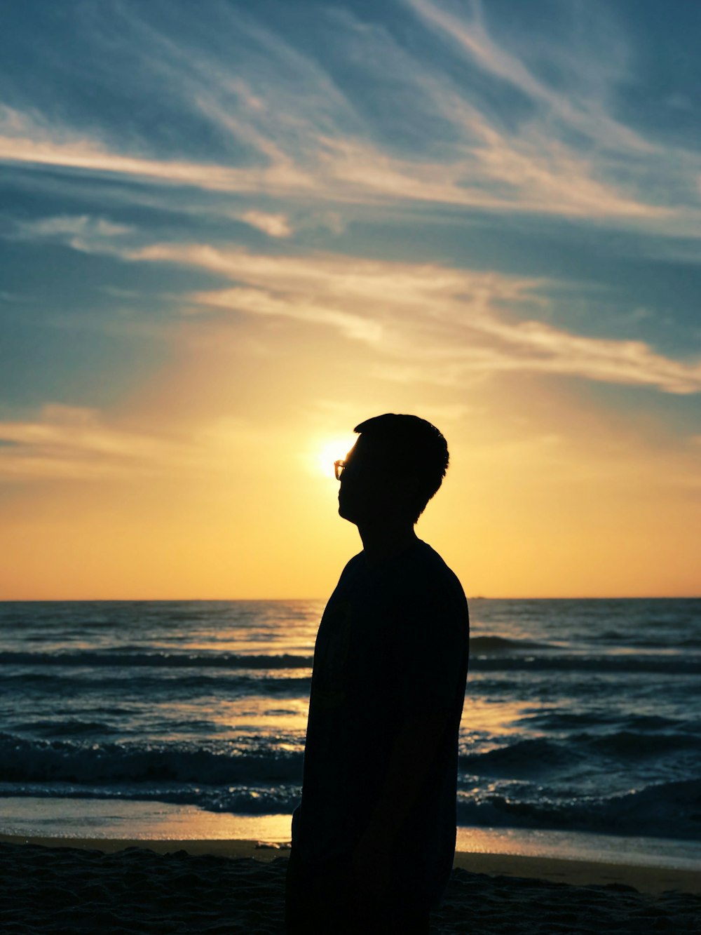 silhouette of man standing on beach during sunset