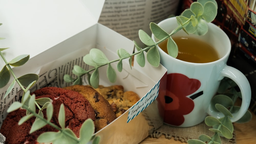 white and red ceramic mug beside brown cookies