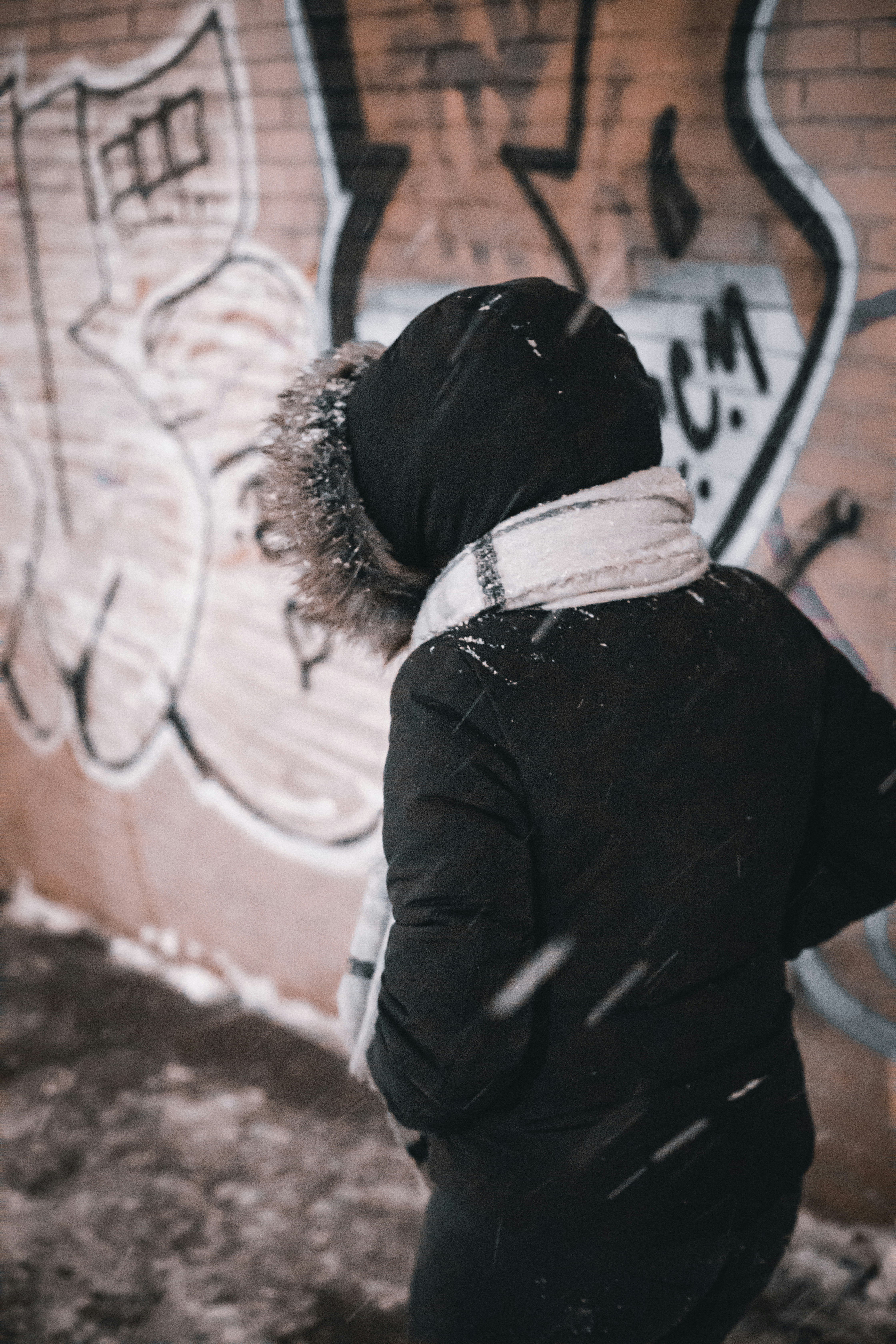 person in black jacket standing near brown wall during daytime