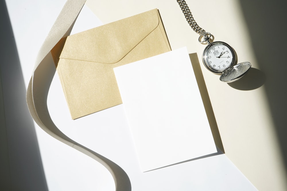 silver round analog watch on white paper