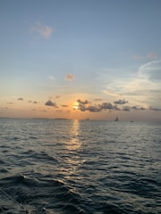 A golden sunset casting warm light over a yacht silhouetted against the horizon.