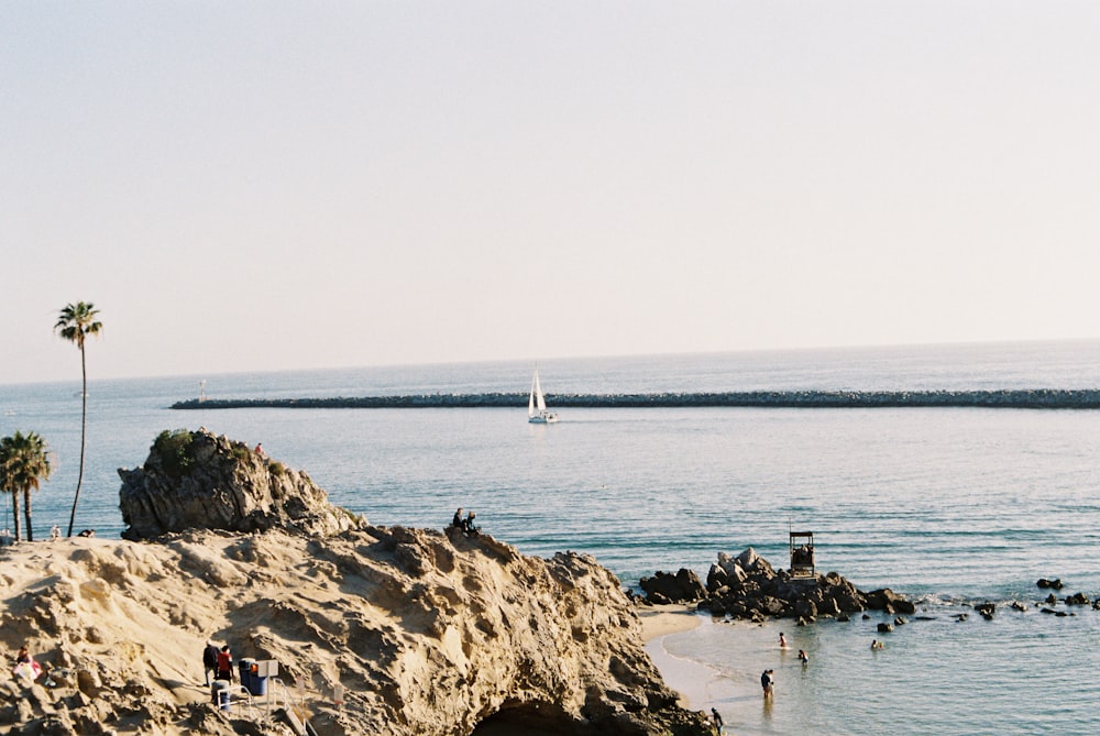 people on brown rock formation near body of water during daytime