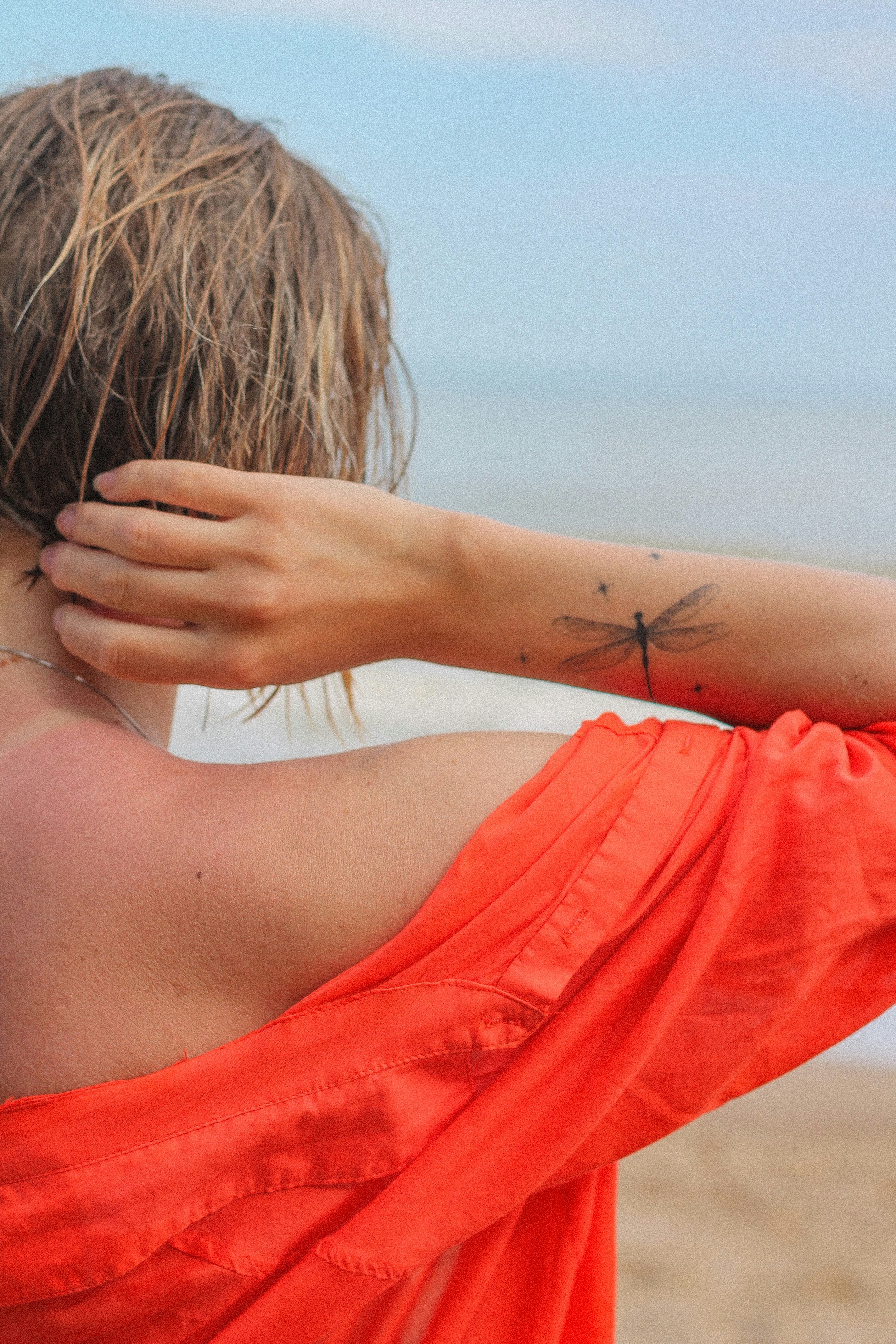 woman in red shirt covering her face with her hair
