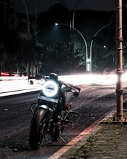 black motorcycle parked on sidewalk during night time
