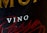 Close-up of a wine label with prominently printed 'VINO' in white text. Surrounding it are larger golden letters partially visible and elegant red script text.