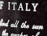 A close-up of a beige t-shirt with a delicate, handwritten Italian phrase about unspoken love