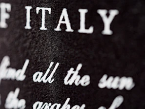 A close-up of a beige t-shirt with a delicate, handwritten Italian phrase about unspoken love