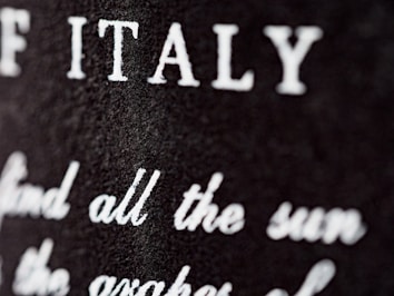 Close-up view of a textured surface with white text partially blurred. The letters are prominently visible, with 'ITALY' clearly noticeable.