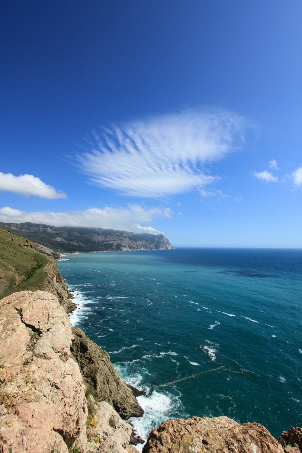 green and brown rocky mountain beside blue sea under blue sky during daytime