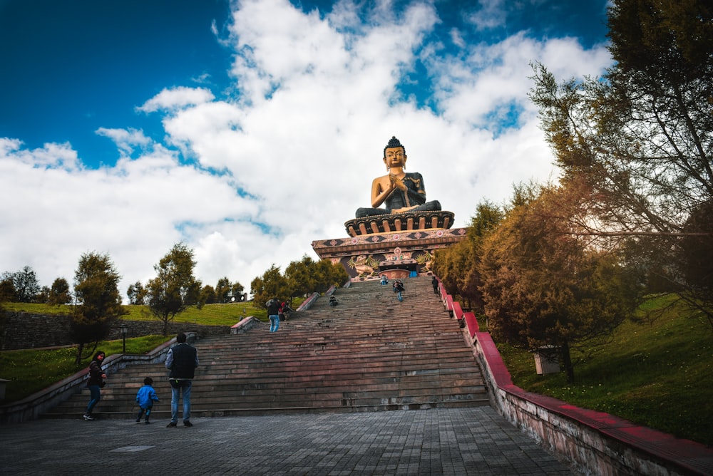 people walking on stairs near brown concrete building under blue and white cloudy sky during daytime