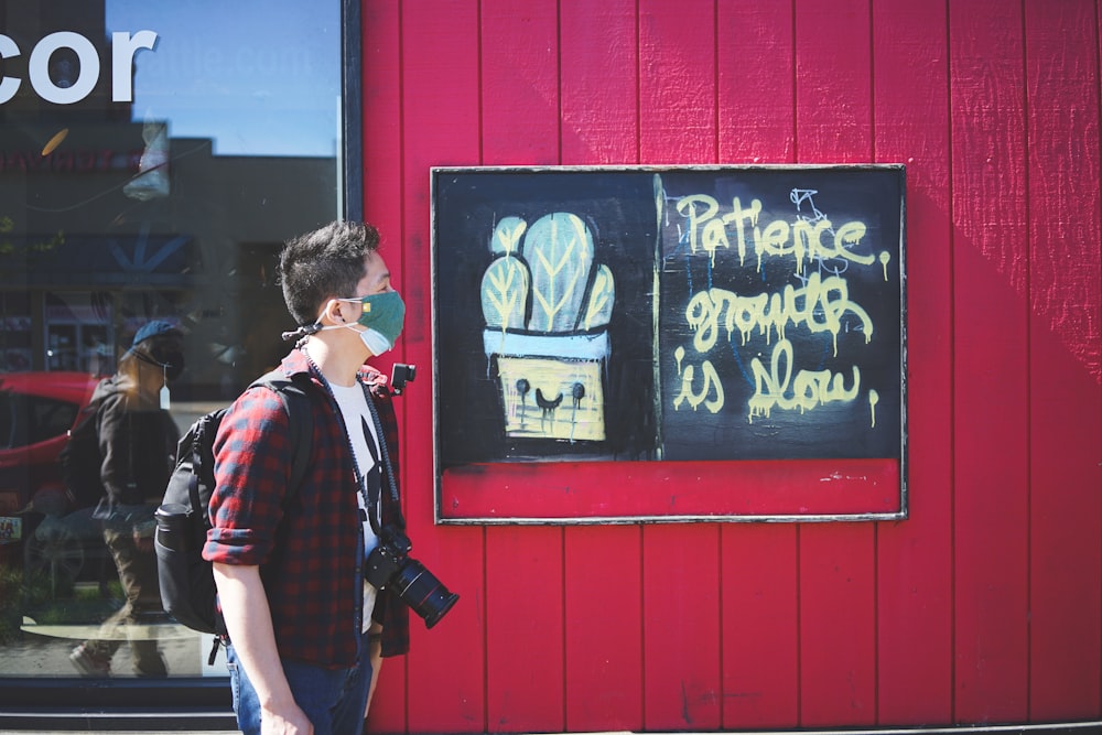 man in red and black jacket standing in front of black and white chalk board