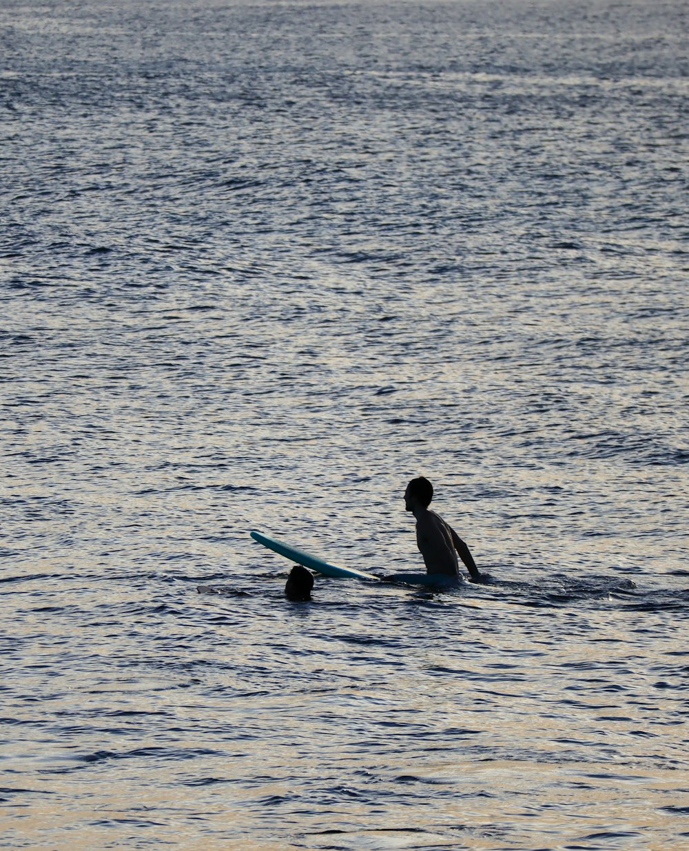 man in black wet suit riding on blue surfboard on body of water during daytime