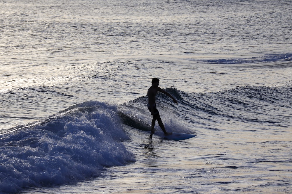 man in black wet suit surfing on sea waves during daytime