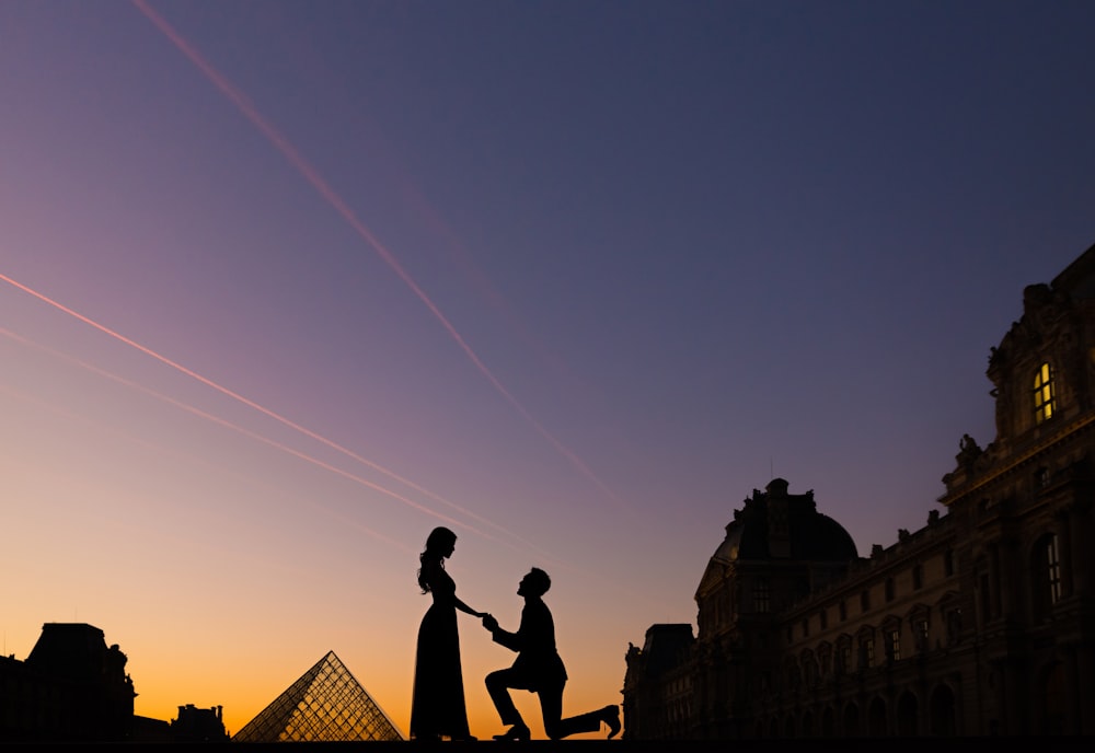 silhouette of man and woman standing on roof top during sunset