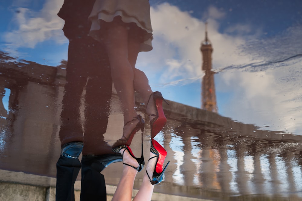 woman in black pants and red and black shoes standing on brown wooden dock during daytime