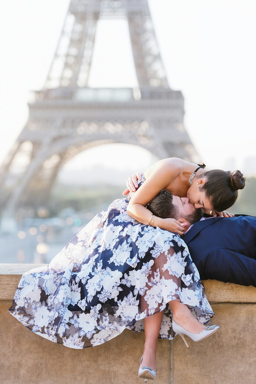 woman in white and black floral dress sitting on brown concrete bench during daytime