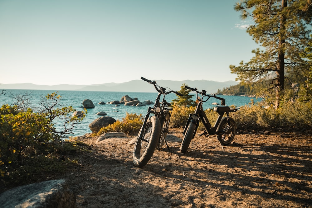 black and gray mountain bike on brown soil near body of water during daytime