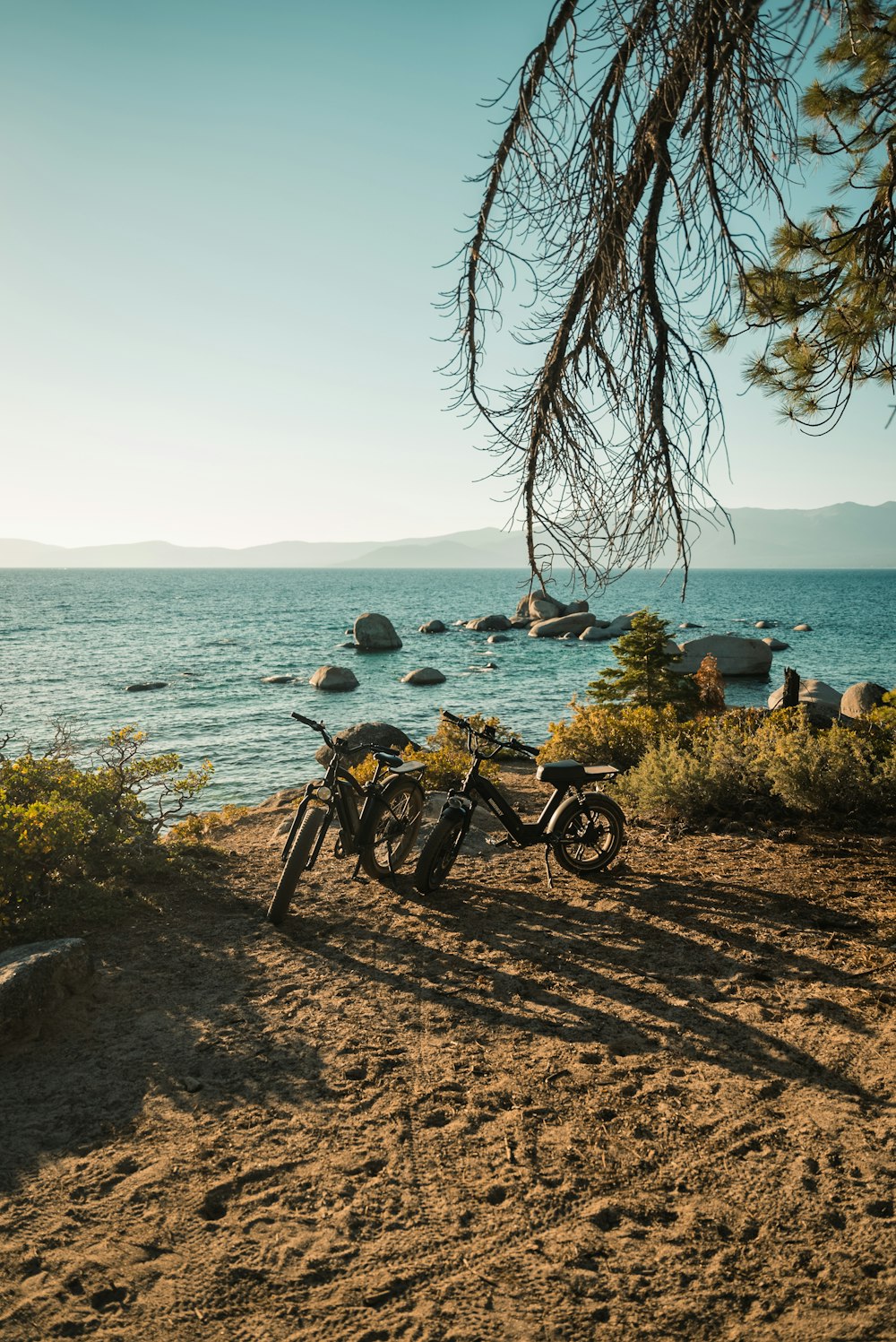 black motorcycle parked beside body of water during daytime