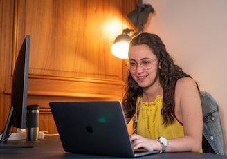 woman in yellow tank top using macbook