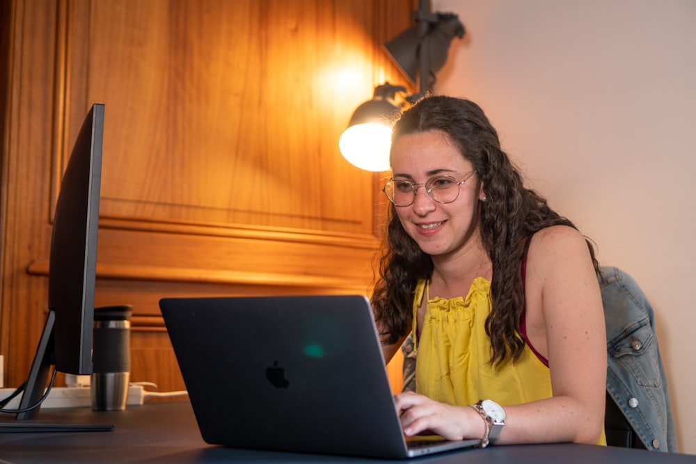 woman in yellow tank top using macbook