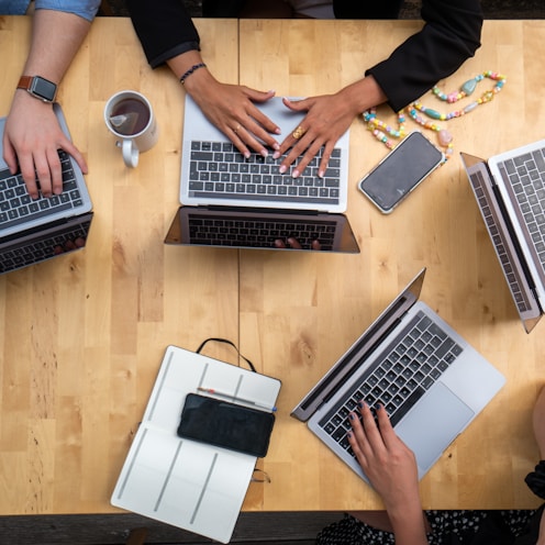 person using macbook pro on brown wooden table