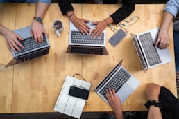 person using macbook pro on brown wooden table