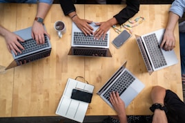 person using macbook pro on brown wooden table