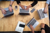 person using macbook pro on brown wooden table