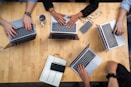 person using macbook pro on brown wooden table