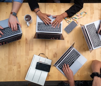 person using macbook pro on brown wooden table