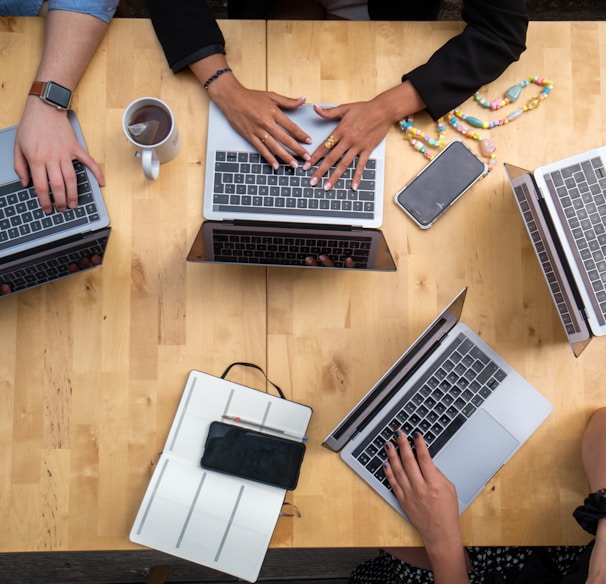 person using macbook pro on brown wooden table