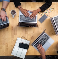 person using macbook pro on brown wooden table