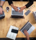 person using macbook pro on brown wooden table