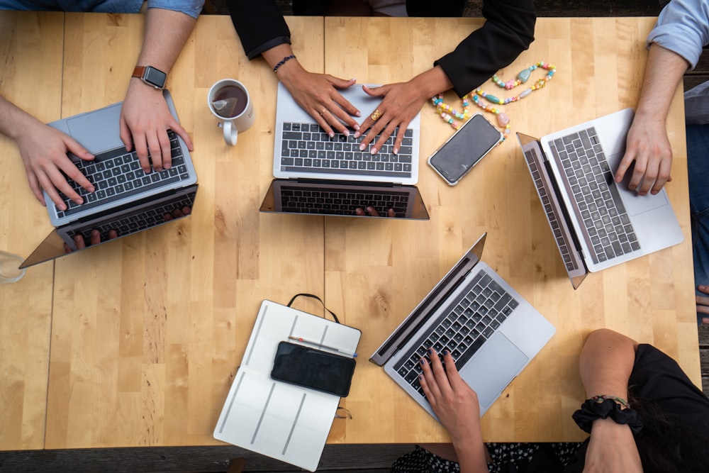 person using macbook pro on brown wooden table