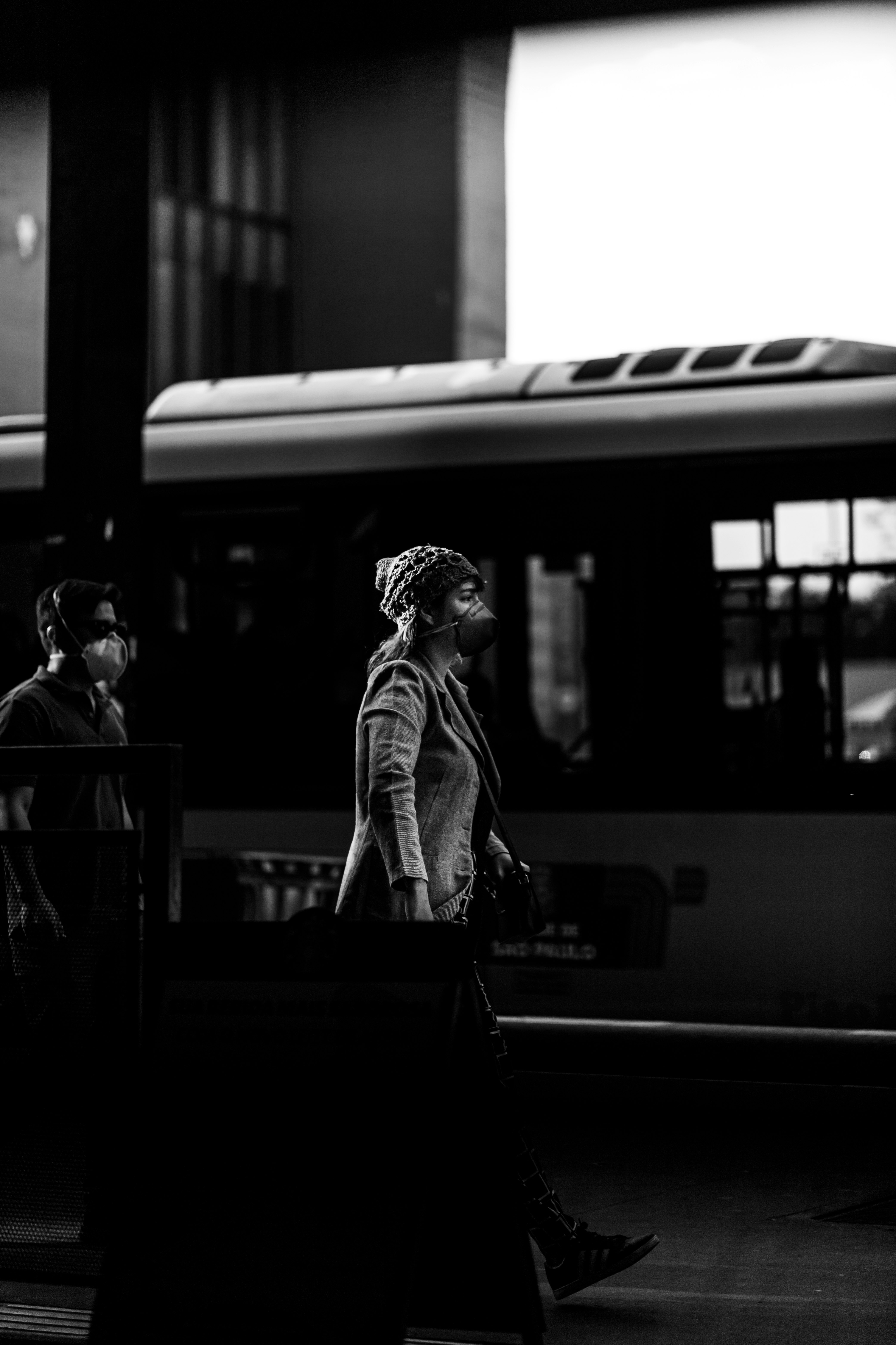 grayscale photo of man and woman standing on train station