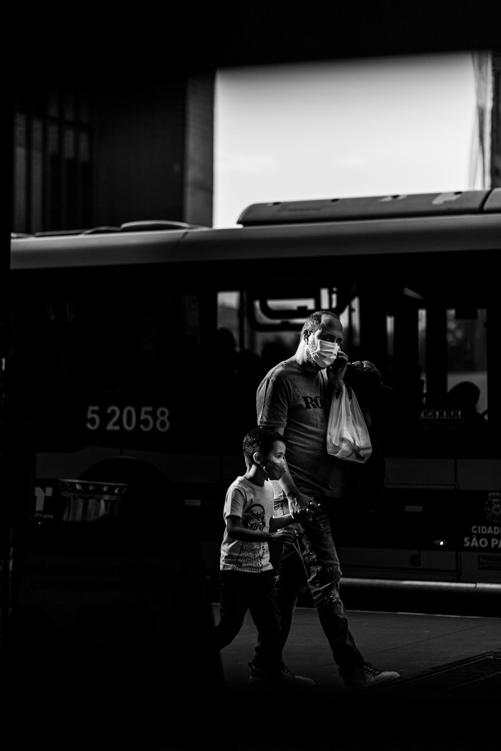 grayscale photo of woman in jacket and jeans standing beside train