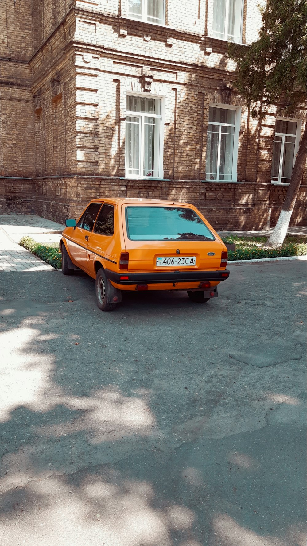 orange 5 door hatchback parked beside brown brick building