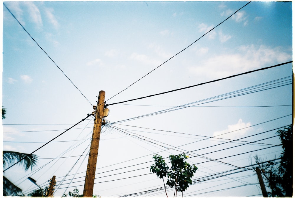 brown wooden electric post under cloudy sky during daytime