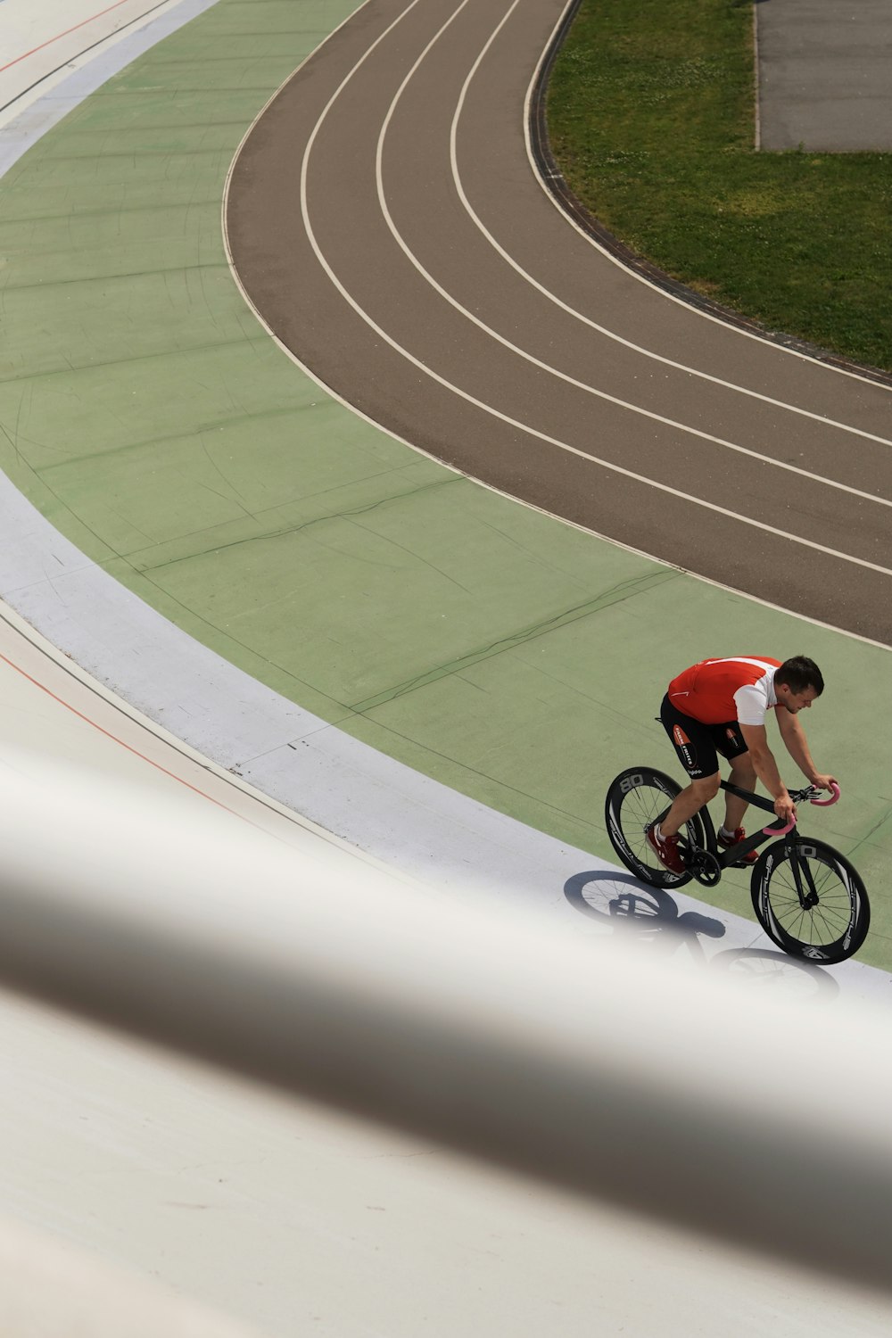 Chico con camisa roja montando en bicicleta en el campo de atletismo durante el día